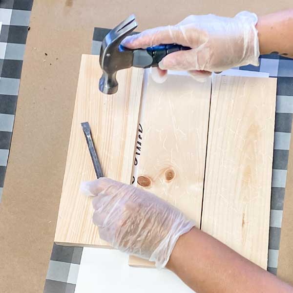 Guest distressing a wood sign using a hammer and metal tool