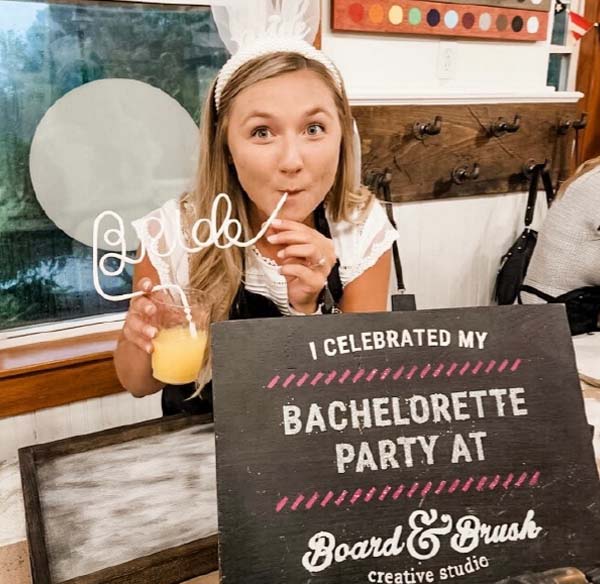 Bride sipping a cocktail with sign